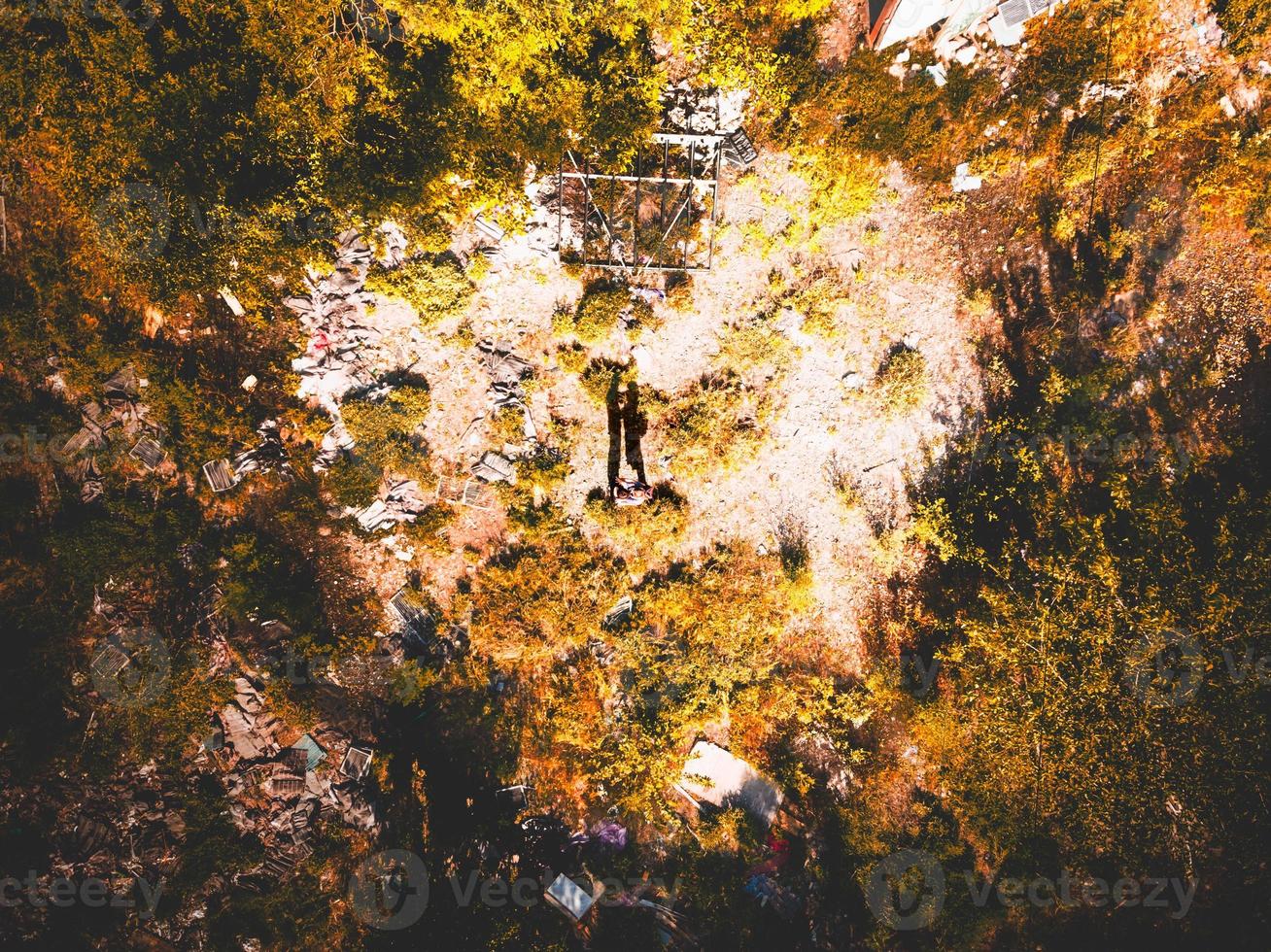 Top down view silhouette of a couple standing in the middle of the heart shaped field with trash around. Dramatic concept of pollution and future generations. Love nature and humans concept photo