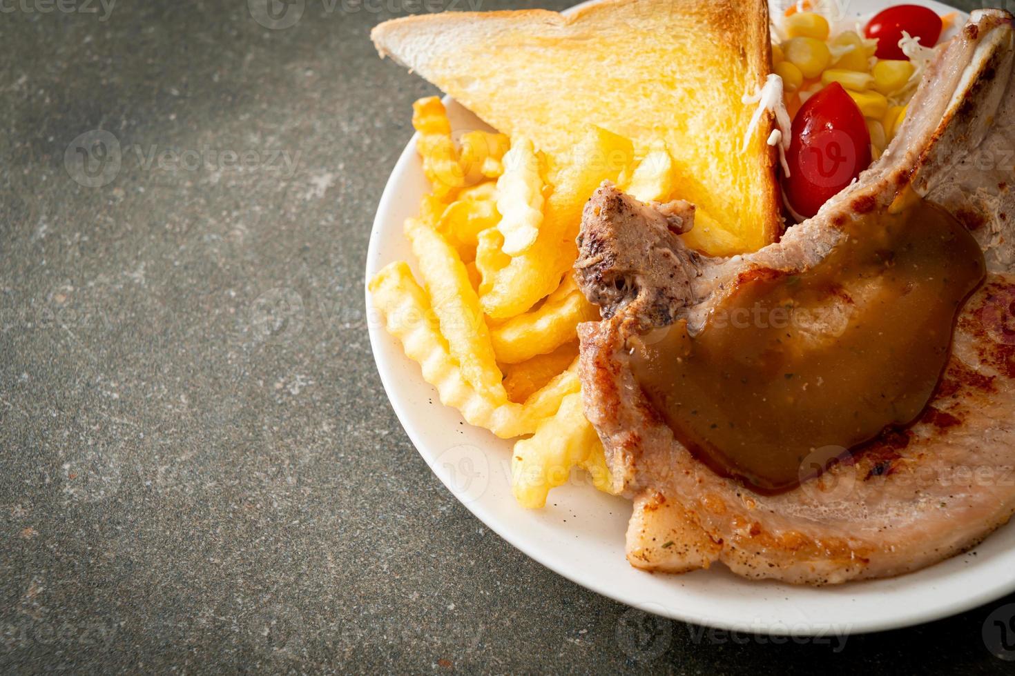 Chuletón de cerdo con patatas fritas y mini ensalada foto