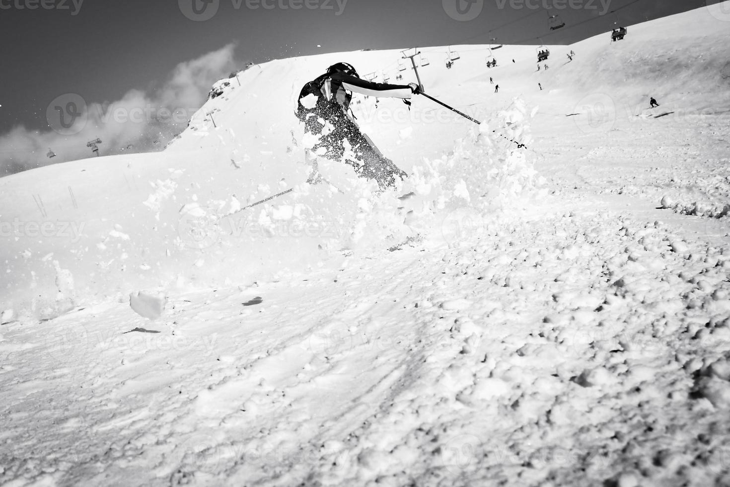 Dynamic picture of a skier on the piste in Alps. Woman skier in the soft snow. Active winter holidays, skiing downhill in sunny day.Ski rides on the track with swirls of fresh snow photo