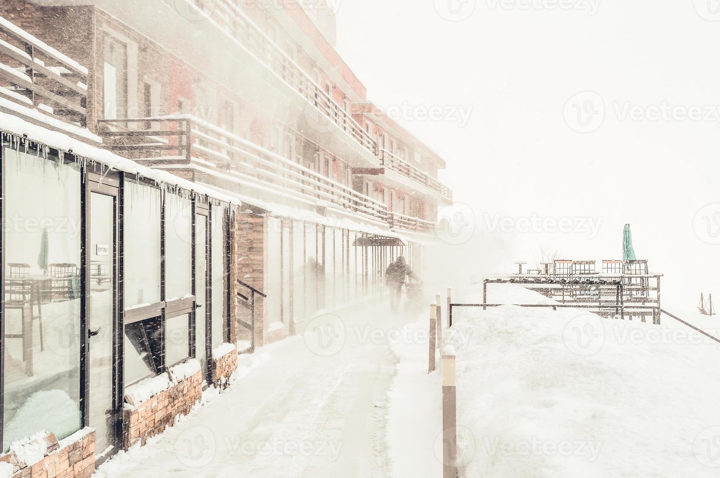 Staff hotel worker clean snow outside in snowy conditions with tractor. Winter holidays and snow problems after heavy snowfall photo