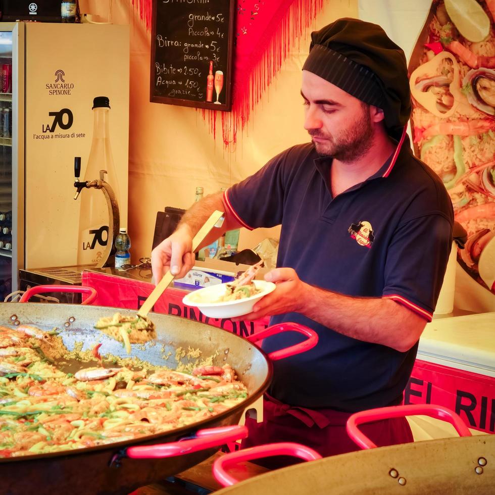 BERGAMO, ITALY - OCTOBER 12, 2014. Man selling paella on a market stall in Bergamo photo