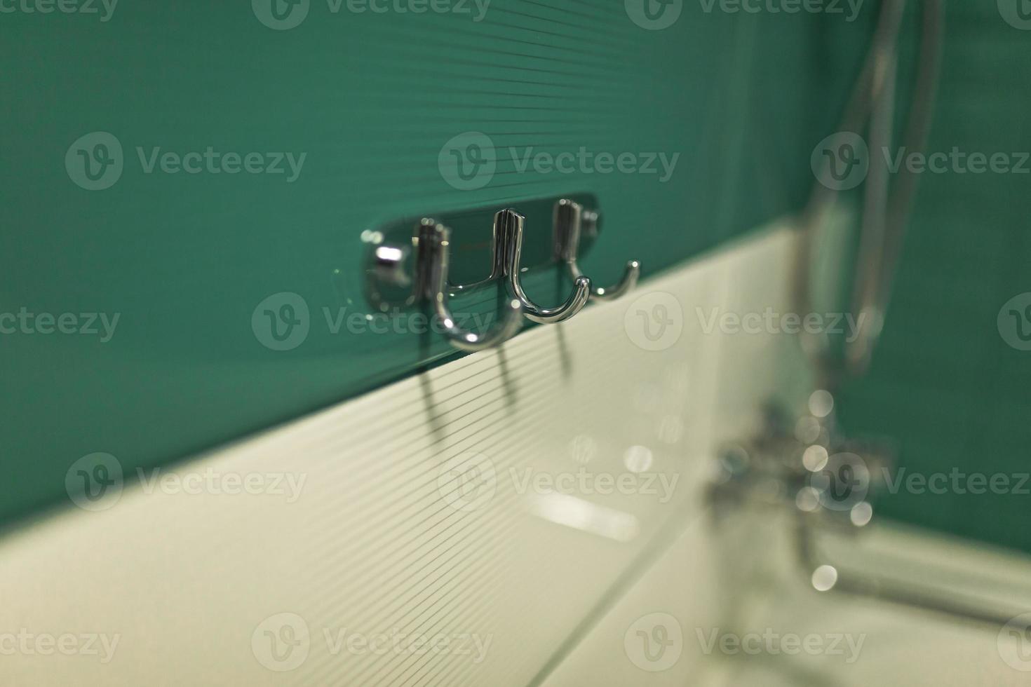 Chrome hook for towel in bathroom. a metal hanger with many hooks for towels and clothes in the bathroom. Shallow depth of field. House, quarter, apartment or hotel. selective focus photo