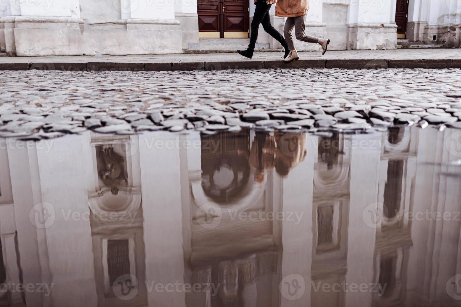 cropped photo of Happy young stylish couple, enjoying their hugging in old road in city street with ancient building on the background. after rain. selective focus