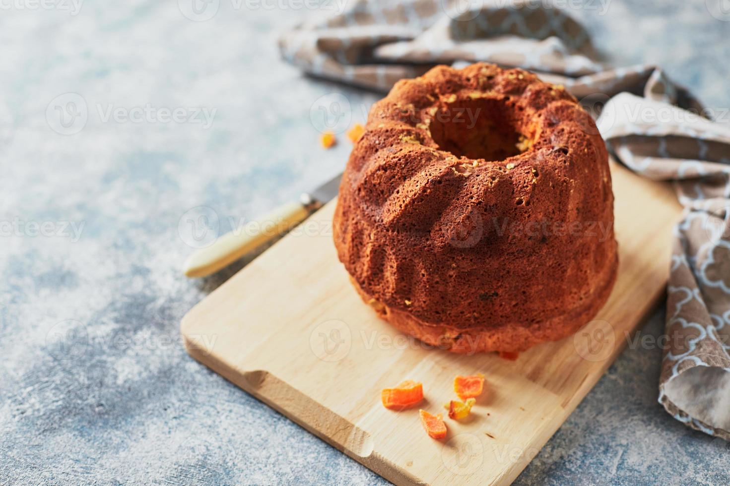 Homemade autumn carrot cake with candied fruits on wooden cutting board photo