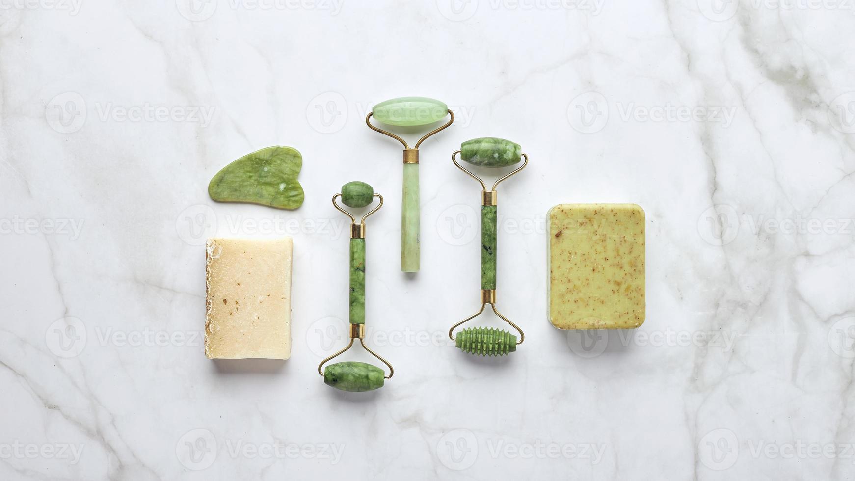 Cosmetic skin care products, jade stone face massager, creams, gel and oil. Roller massage of the face. Flat lay, top view photo