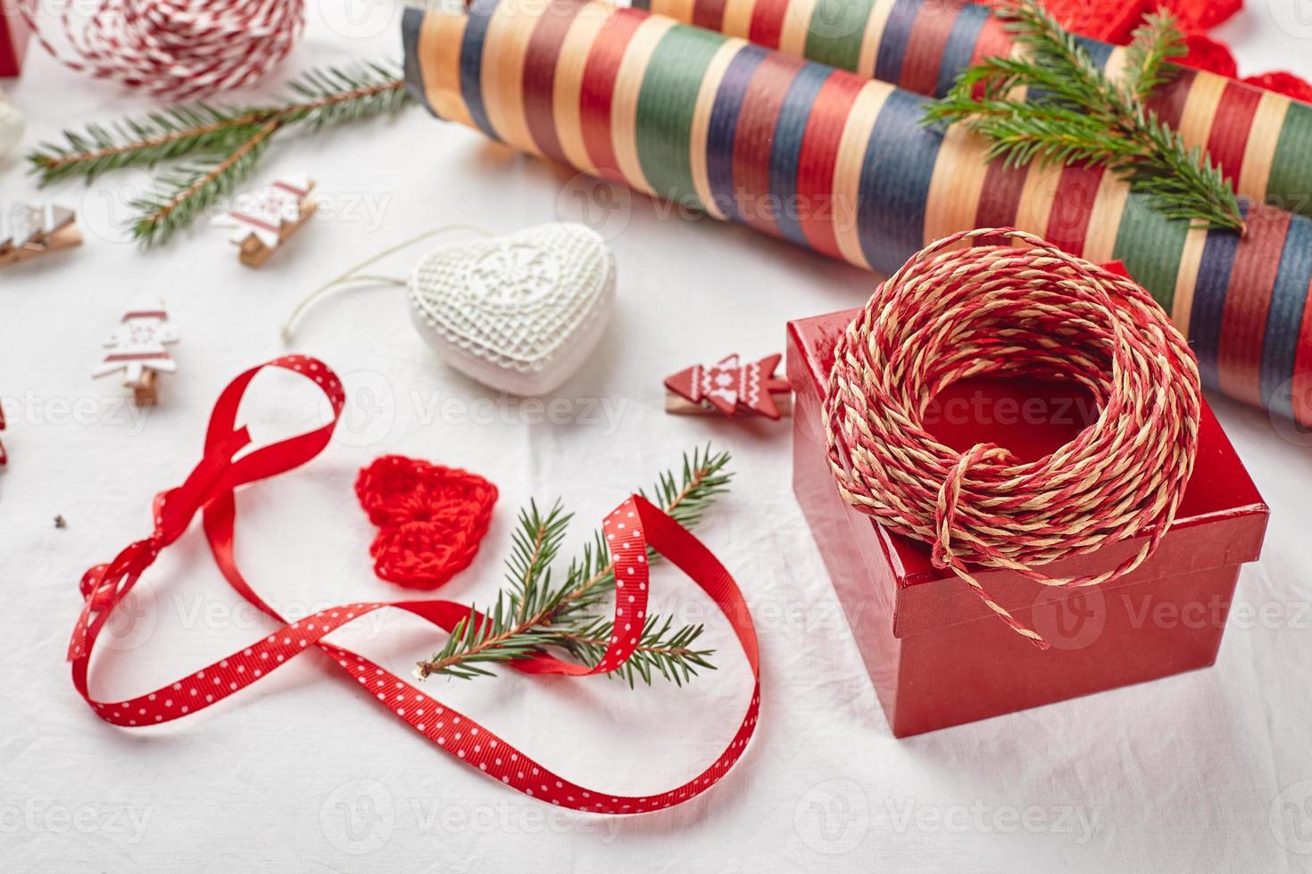Christmas background with gift boxes, ribbon, twine, paper rolls, knitted hearts and Christmas ornament. photo