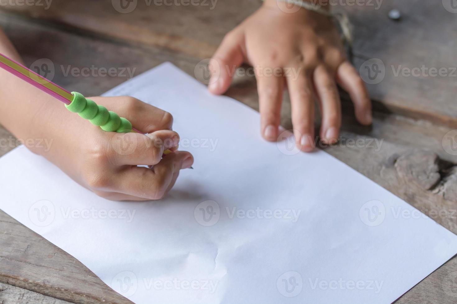 niños de la mano escribiendo con lápiz foto