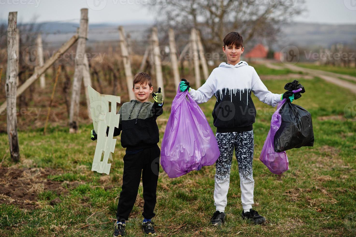 Brothers with trash bag collecting garbage while cleaning in the vineyards . Environmental conservation and ecology, recycling. photo