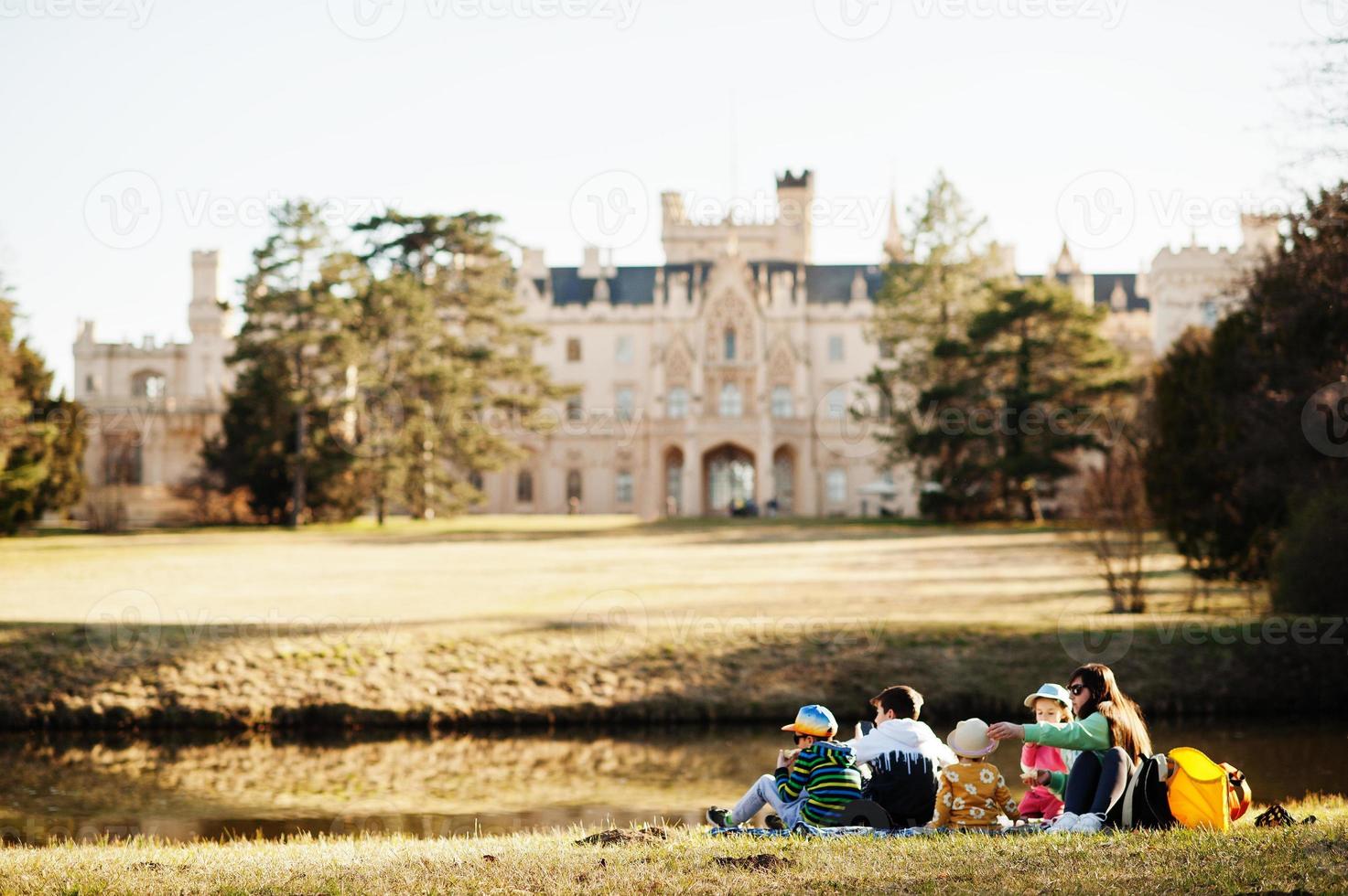 Mother with four kids having picnic near pound at Lednice park against castle, Czech Republic. photo