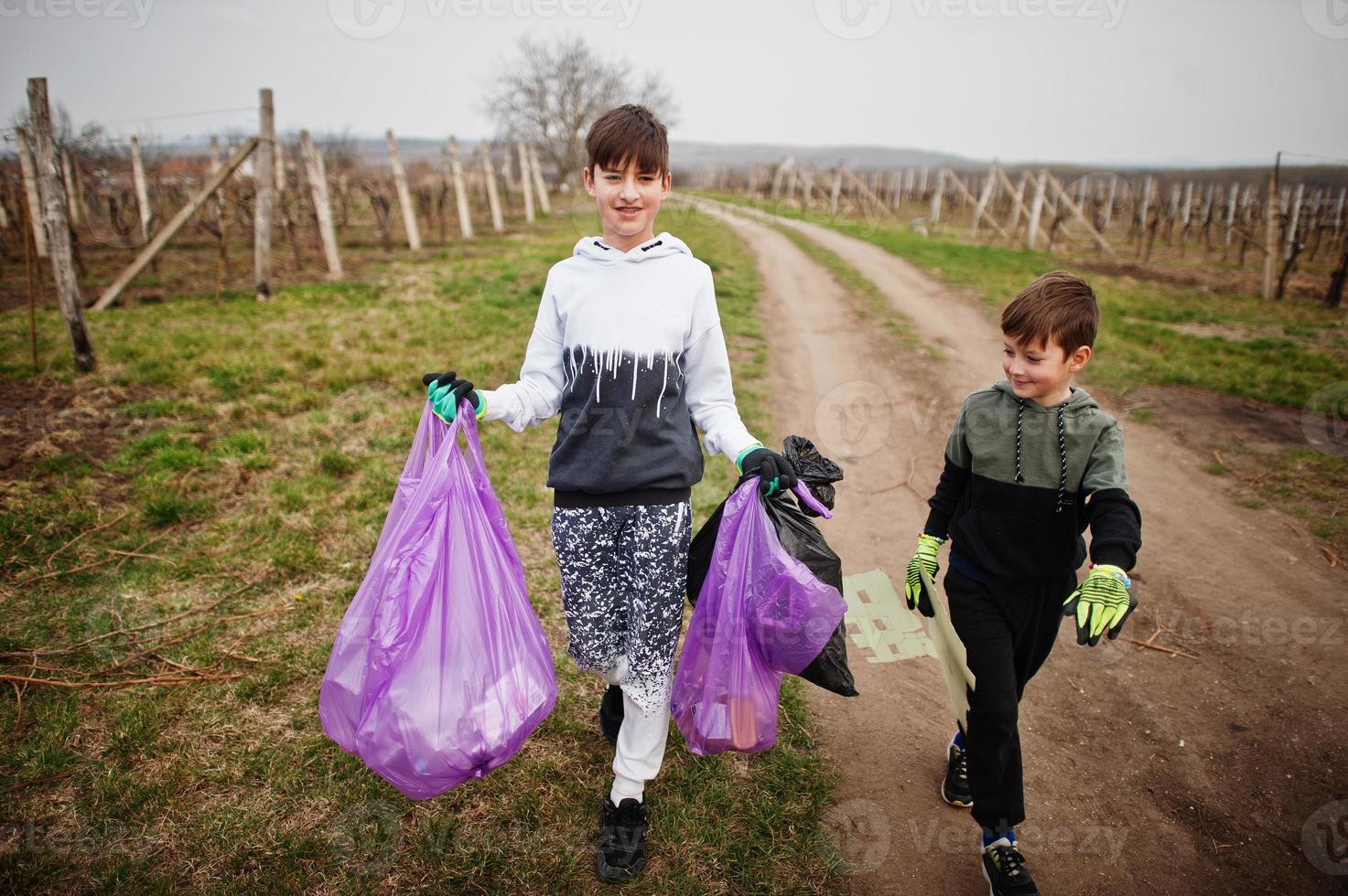 Brothers with trash bag collecting garbage while cleaning in the vineyards . Environmental conservation and ecology, recycling. photo