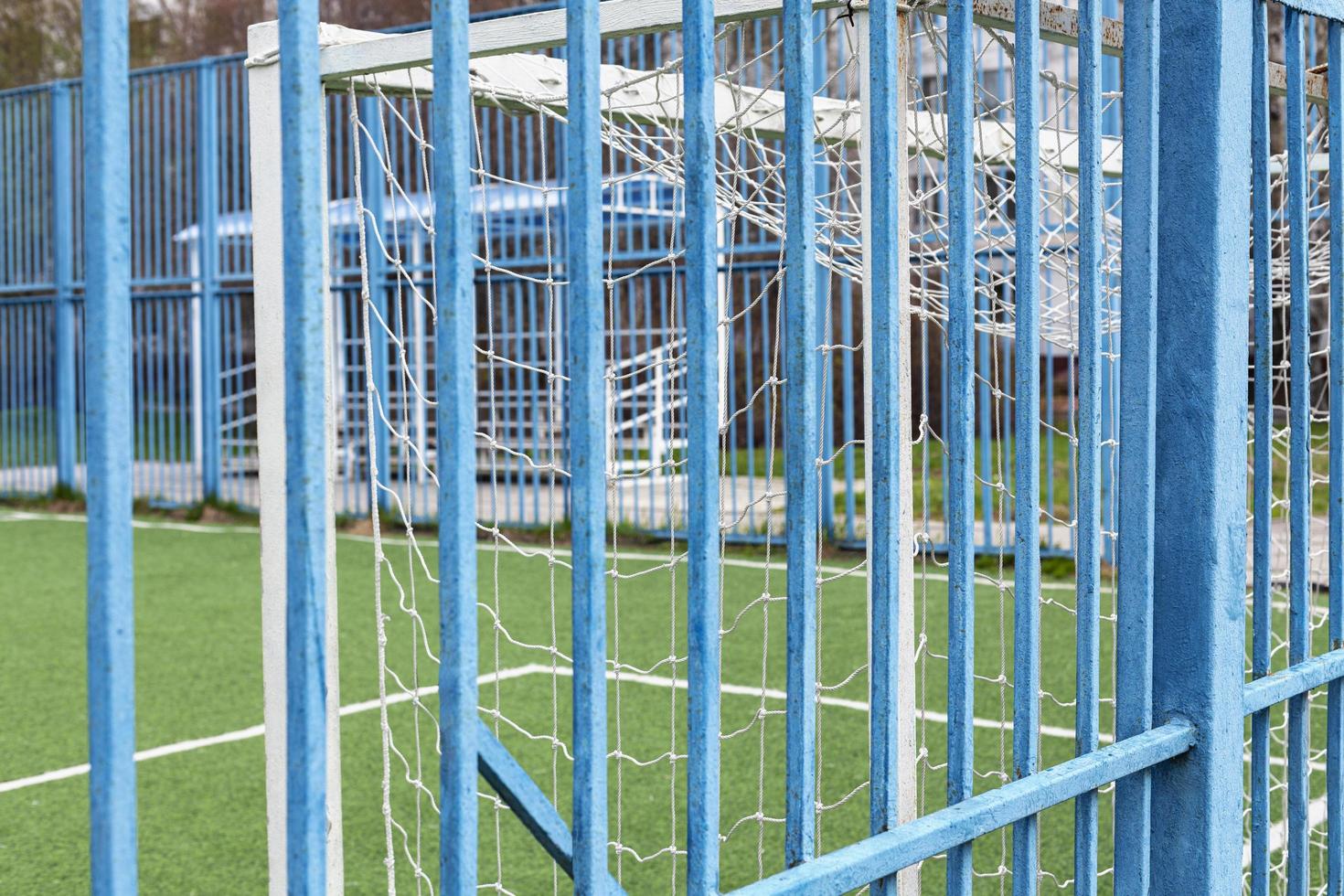 Football field. View of the football field with white goals through the blue fence. Sports concept, soccer field and soccer goal with grass floor. photo