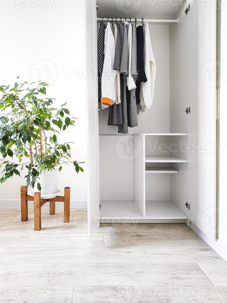 Wardrobe with basic clothes in room scandi interior. photo