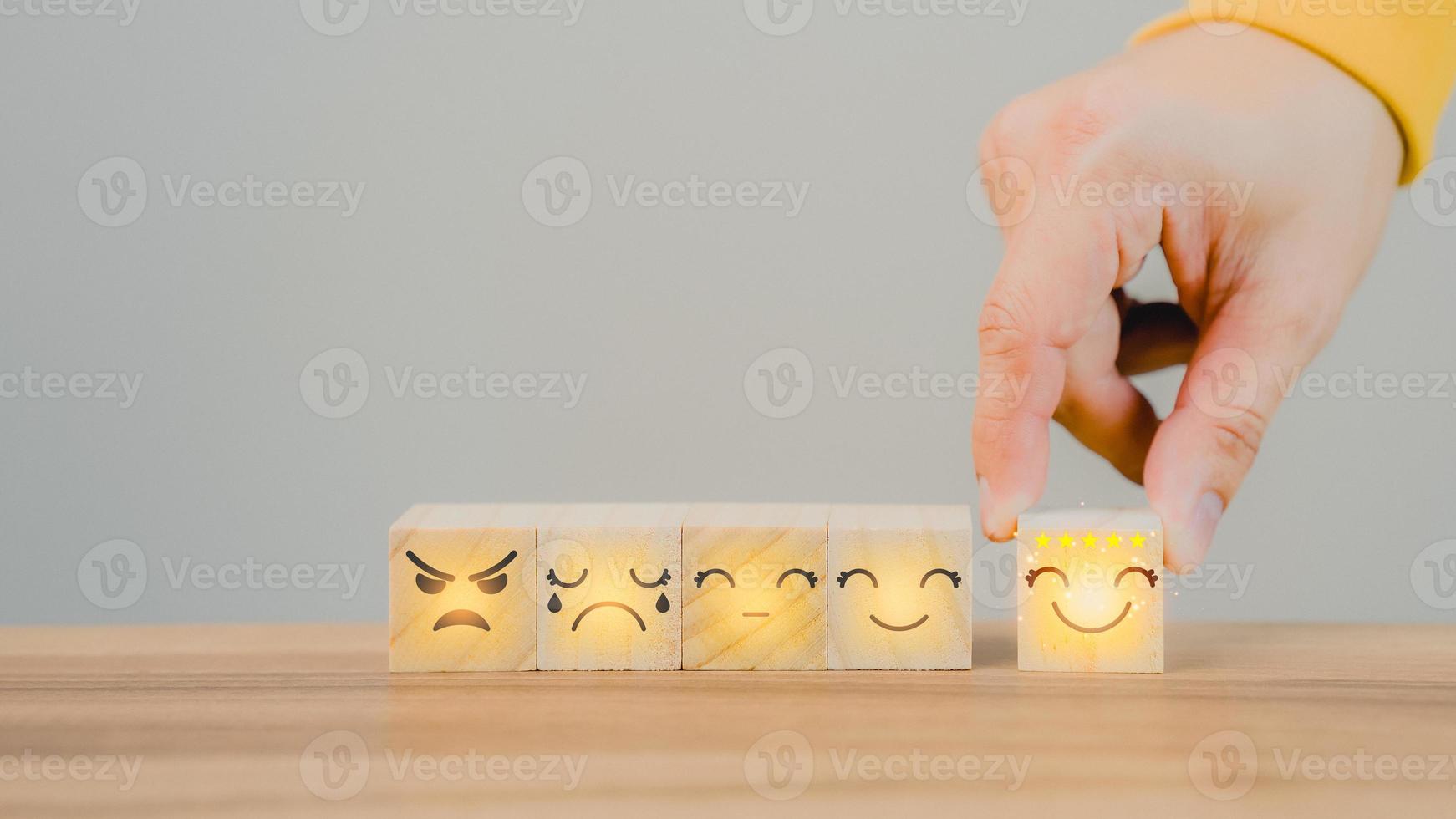 Customer's hand selects a smiley face on a wooden cube block 5 Star Satisfaction. Best Great business services rate the customer experience. Satisfaction Survey Concept. photo