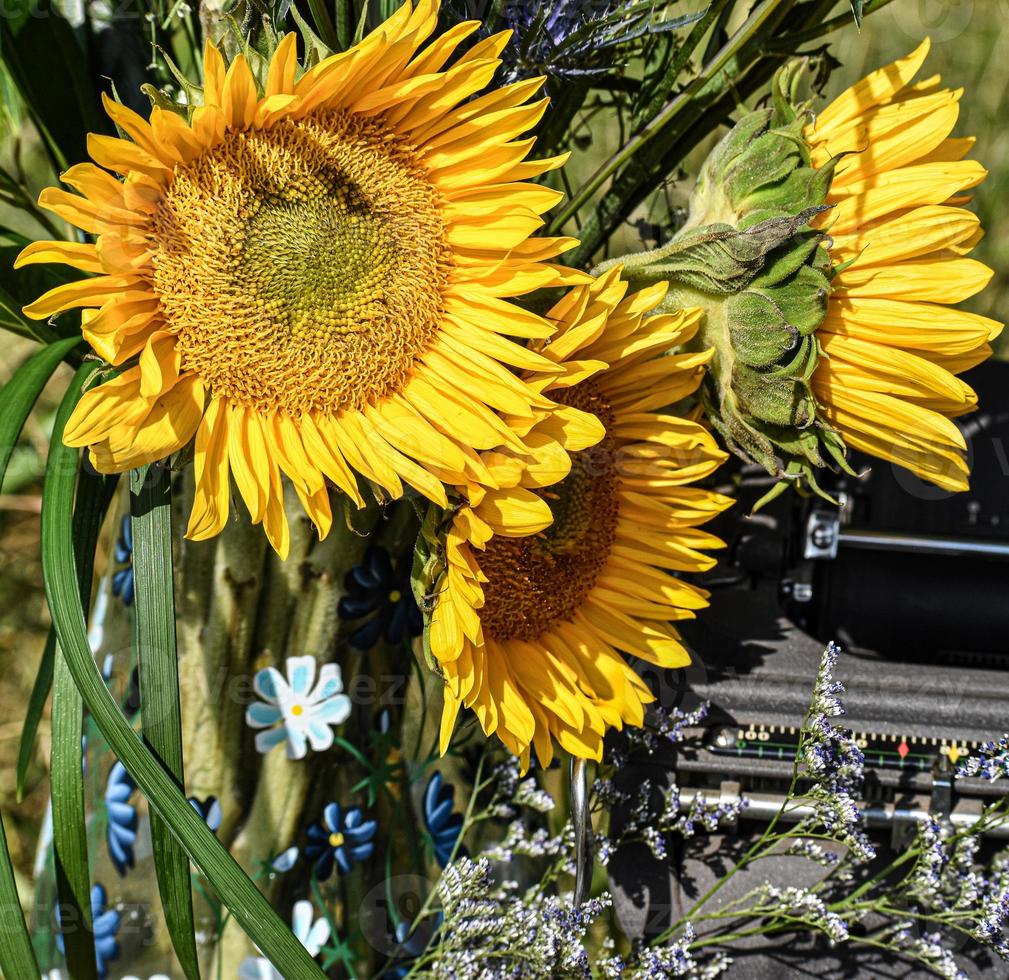 Glass Vase Of Sunflowers Next To A Typewriter photo