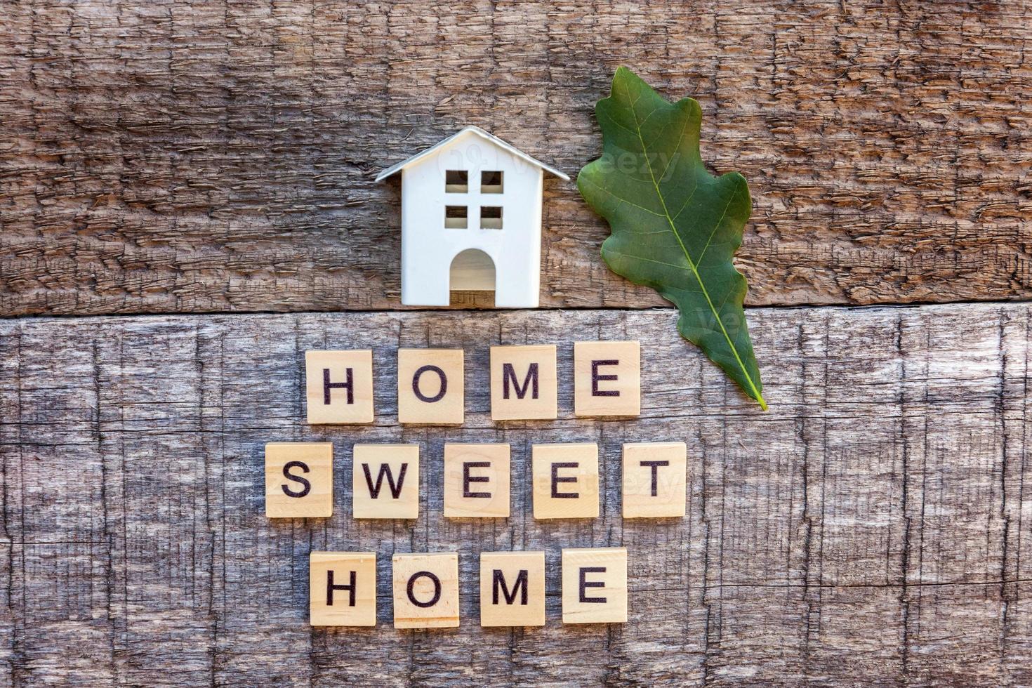 Miniature toy model house with inscription HOME SWEET HOME letters word on wooden background photo