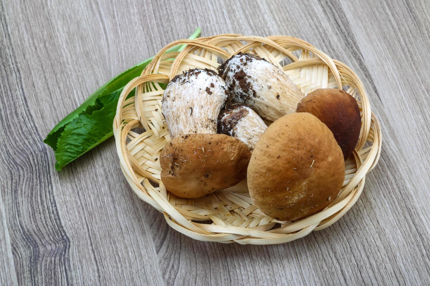 hongos silvestres en una canasta sobre fondo de madera foto