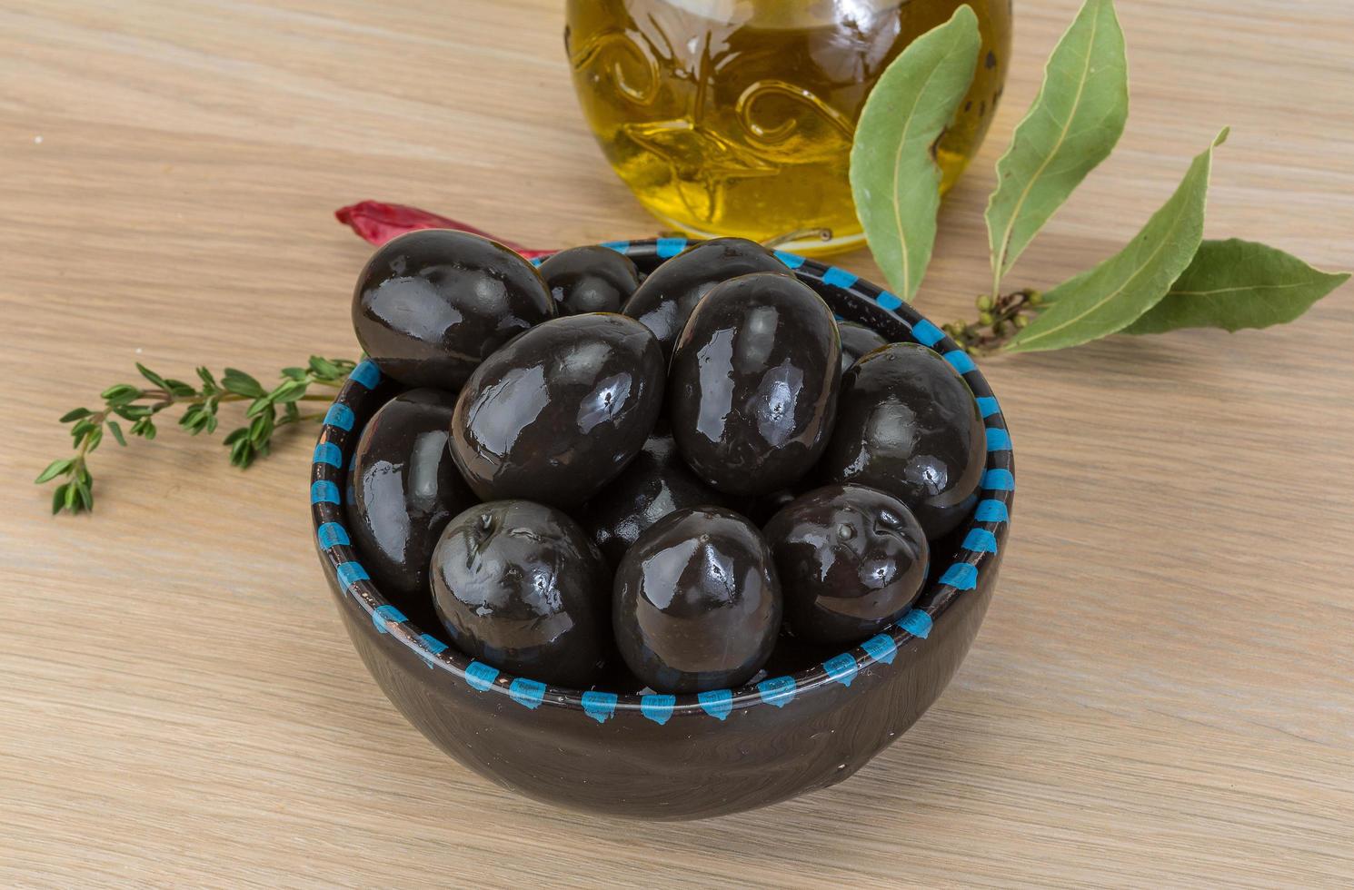 Black olives in a bowl on wooden background photo