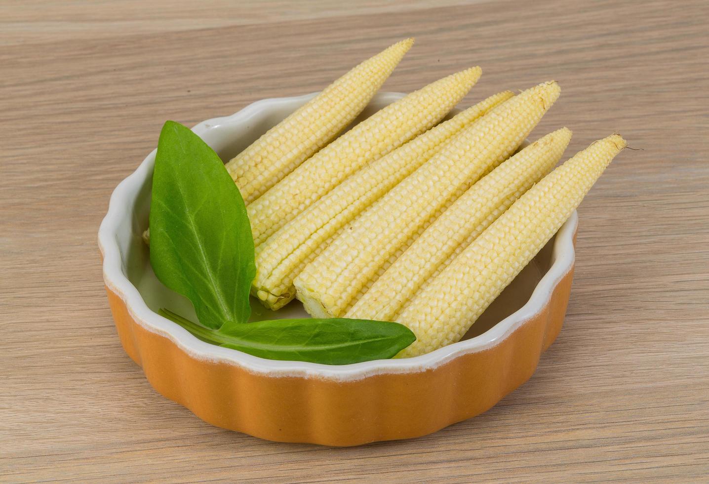 Baby corn in a bowl on wooden background photo