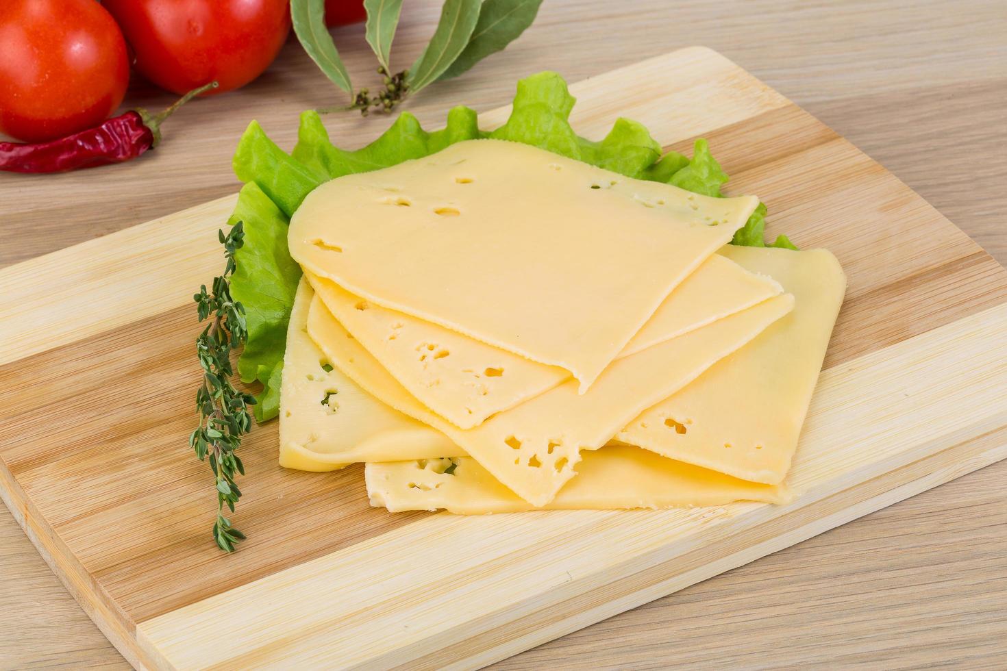 Sliced cheddar on wooden board and wooden background photo