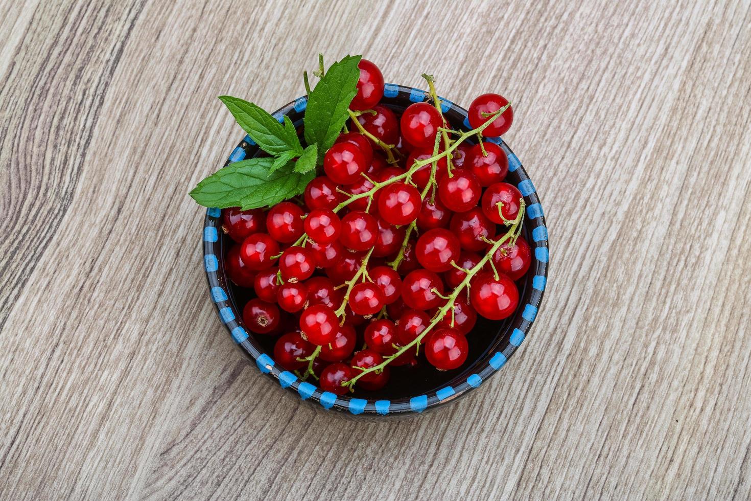 Red currants in a bowl on wooden background photo