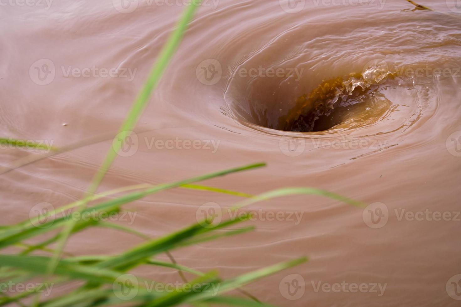 A powerful vortex is created at the green surface of the river flowing vigorously from torrential rains and floods. photo