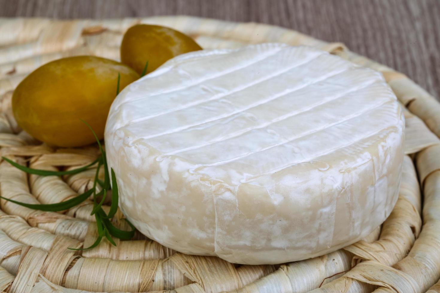 queso brie sobre tablero de madera y fondo de madera foto