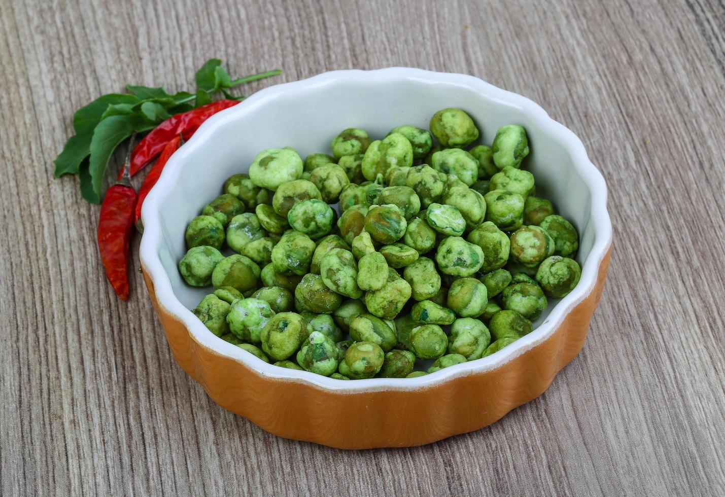 Wasabi peas in a bowl on wooden background photo