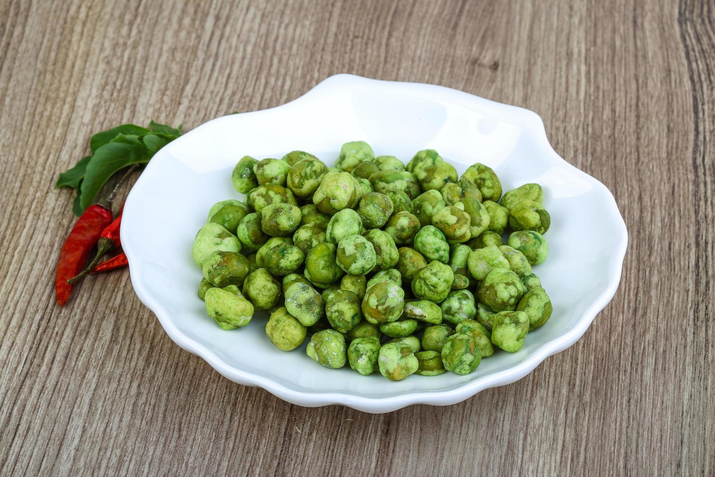 Wasabi peas on the plate and wooden background photo