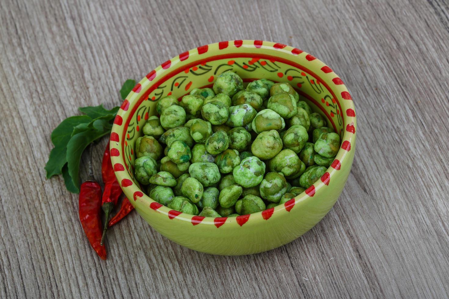 Wasabi peas in a bowl on wooden background photo