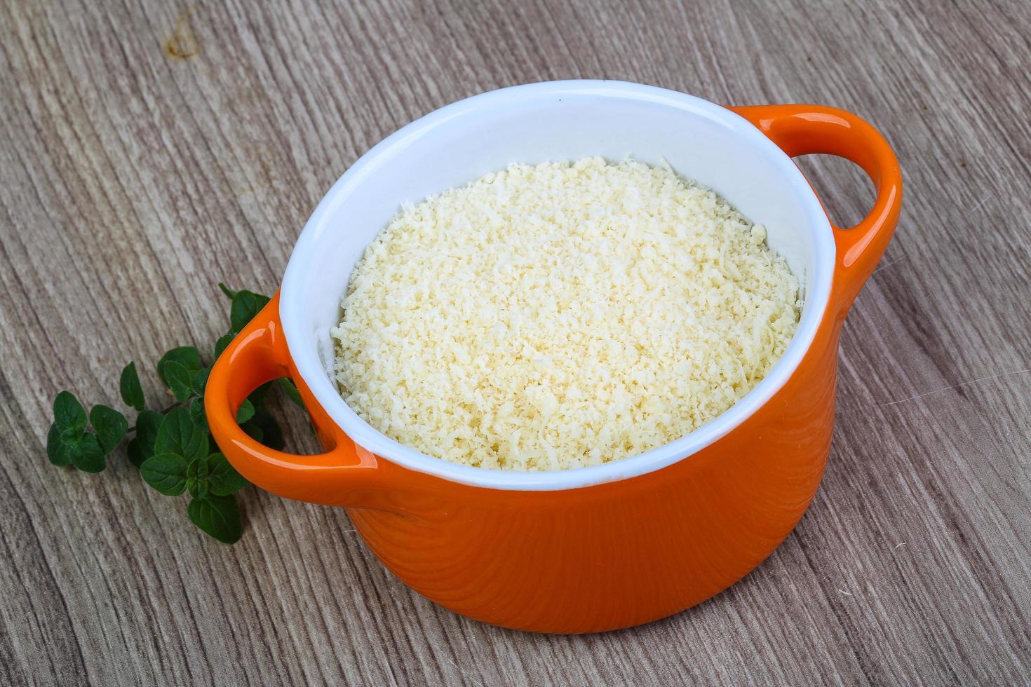 Shredded parmesan in a bowl on wooden background photo