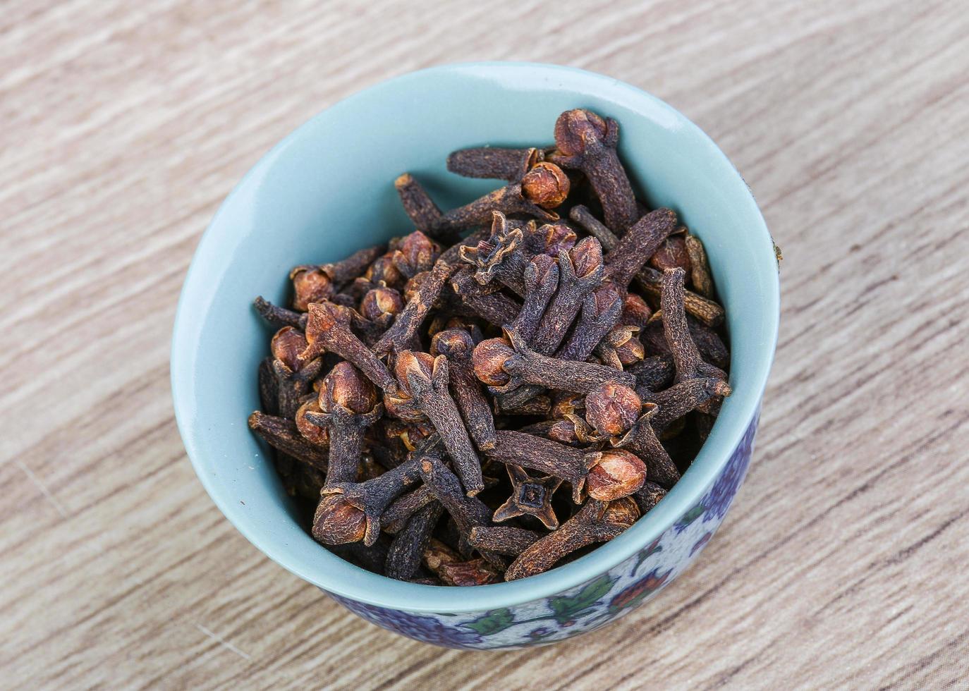 Cloves seeds in a bowl on wooden background photo