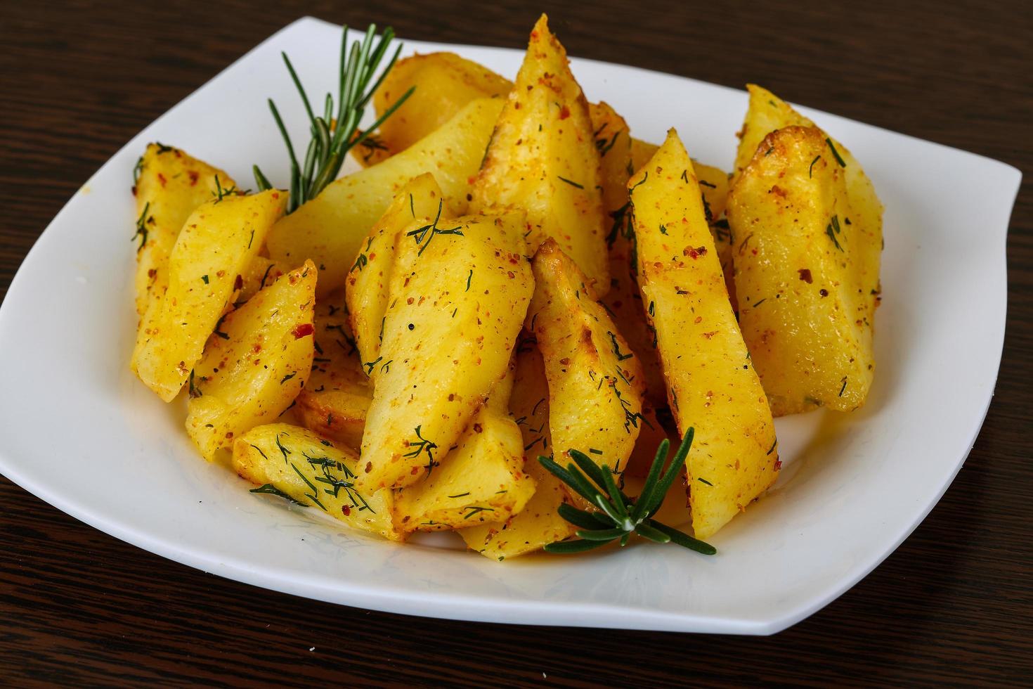 Roasted potato on the plate and wooden background photo