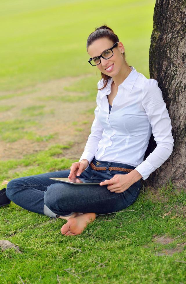 Beautiful young woman with  tablet in park photo