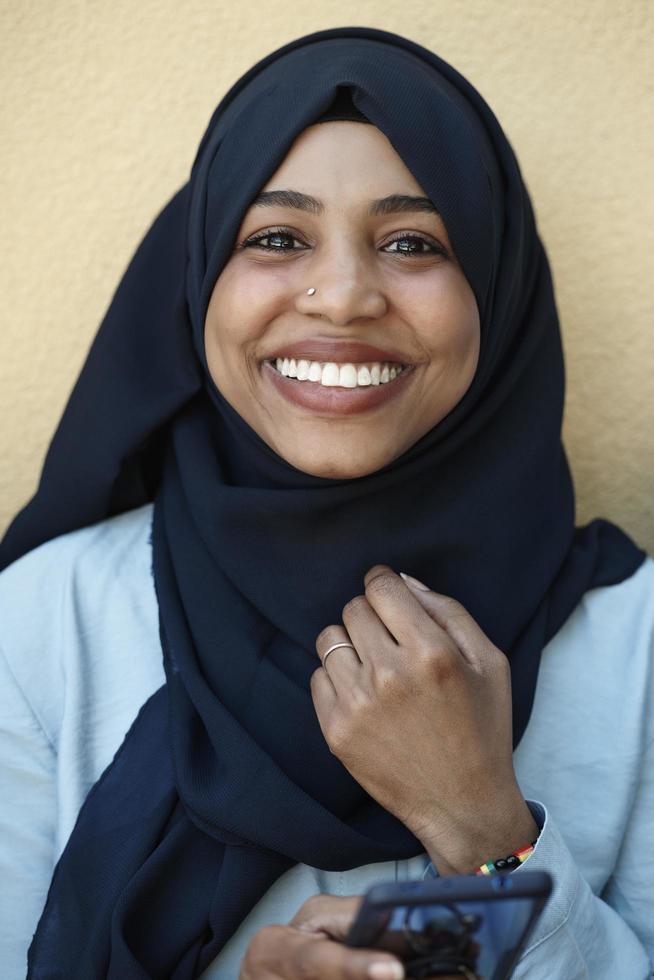african  woman using smartphone wearing traditional islamic clothes photo