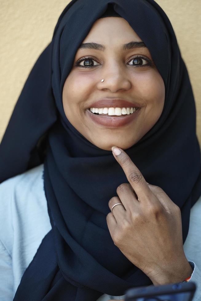 african  woman using smartphone wearing traditional islamic clothes photo