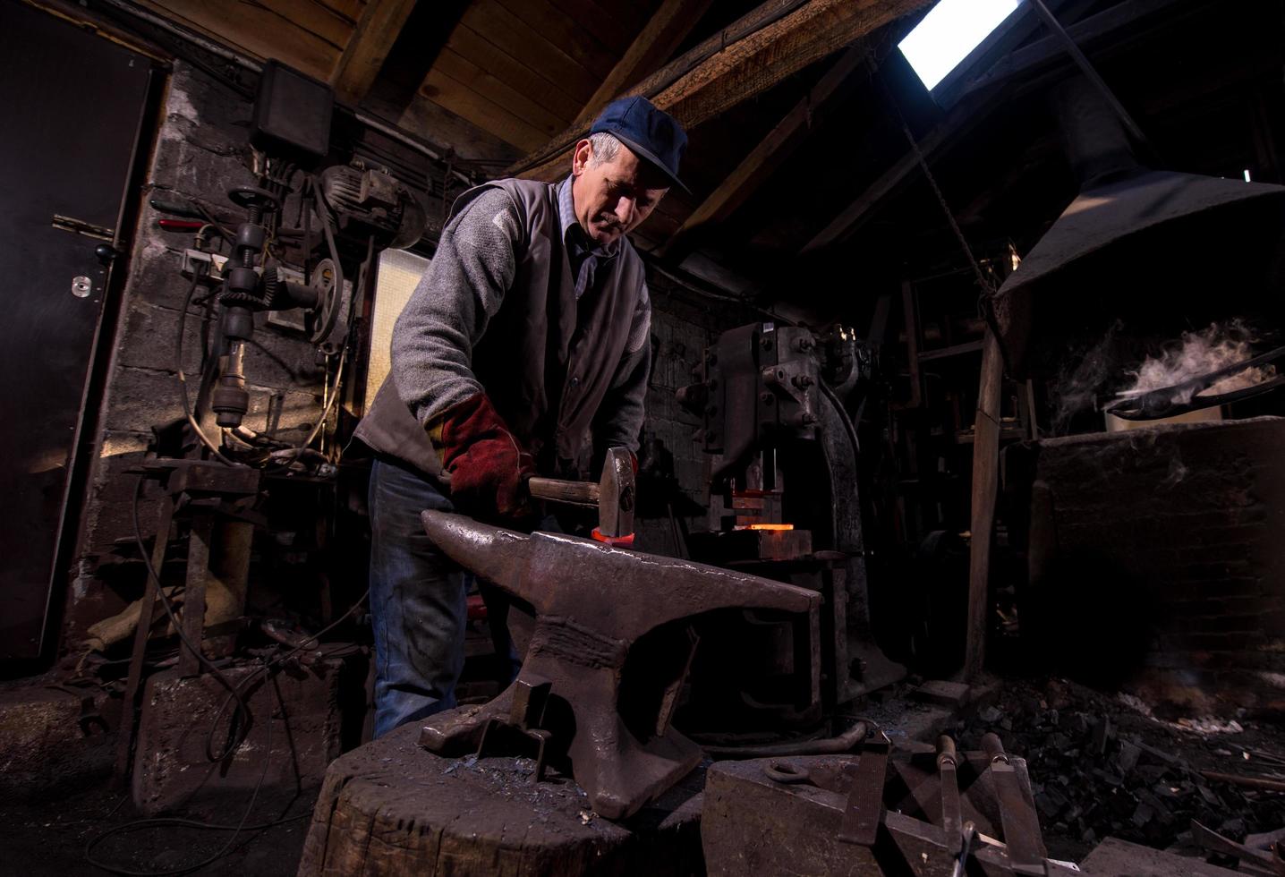 blacksmith manually forging the molten metal photo