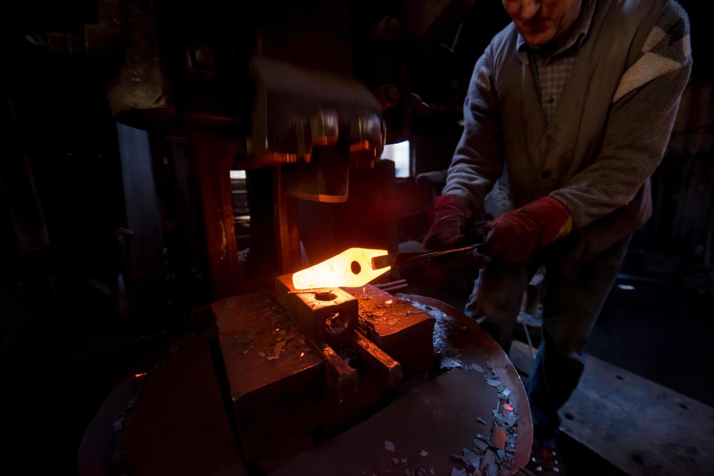 blacksmith manually forging the molten metal photo