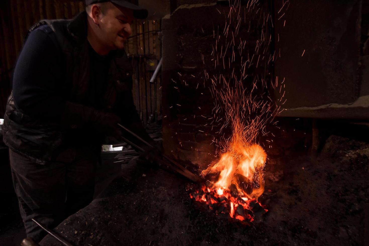 young traditional Blacksmith working with open fire photo