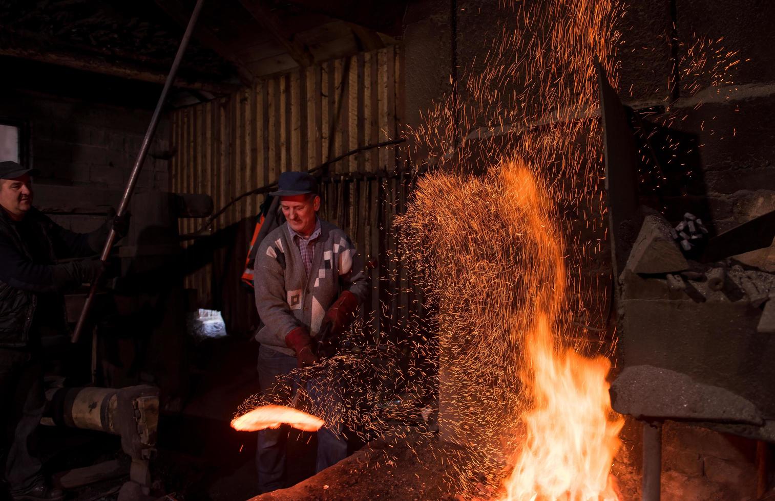 trabajadores del herrero que usan el martillo mecánico en el taller foto