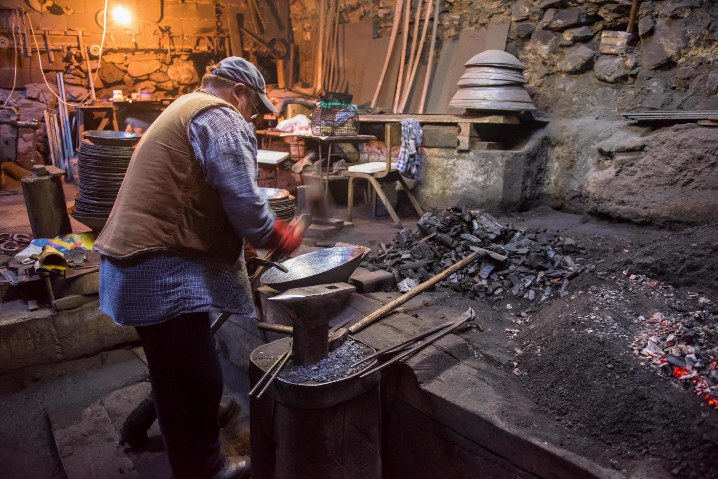 herrero tradicional que forja manualmente el metal fundido foto