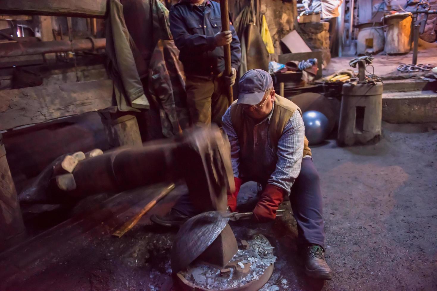 trabajadores del herrero que usan el martillo mecánico en el taller foto