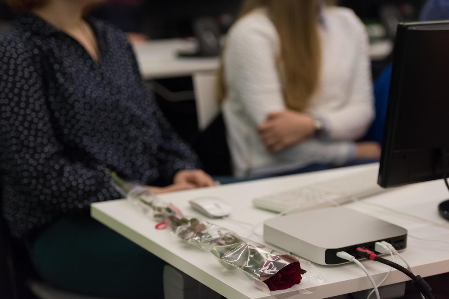 flor de rosa en la mesa de los estudiantes de famale en clase foto