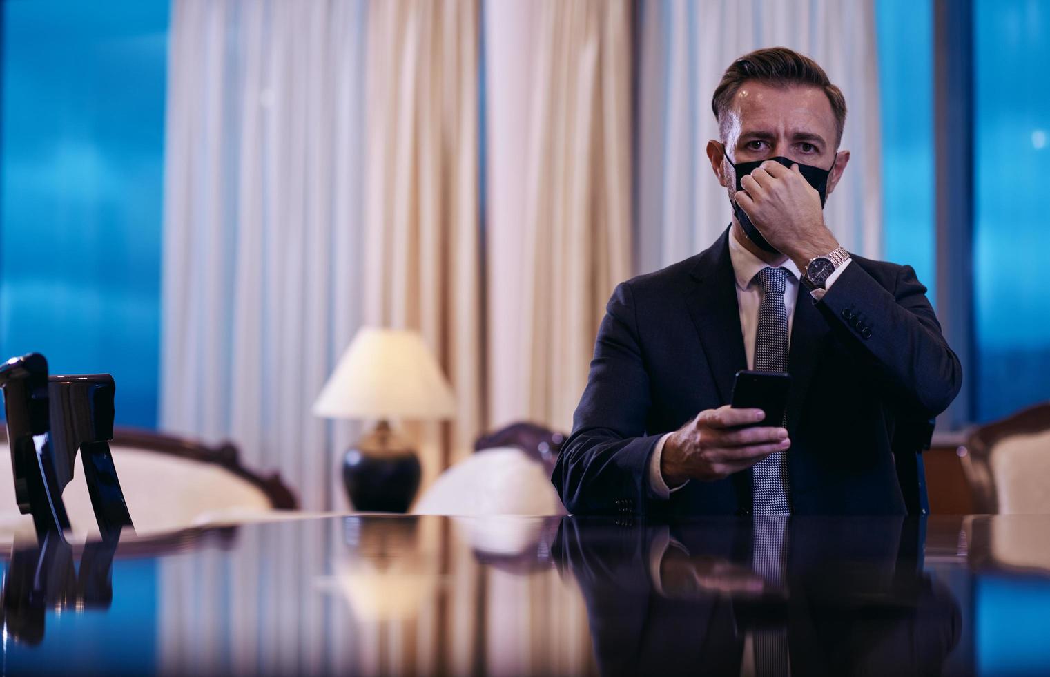 business man using smart phone at luxury office wearing face mask photo