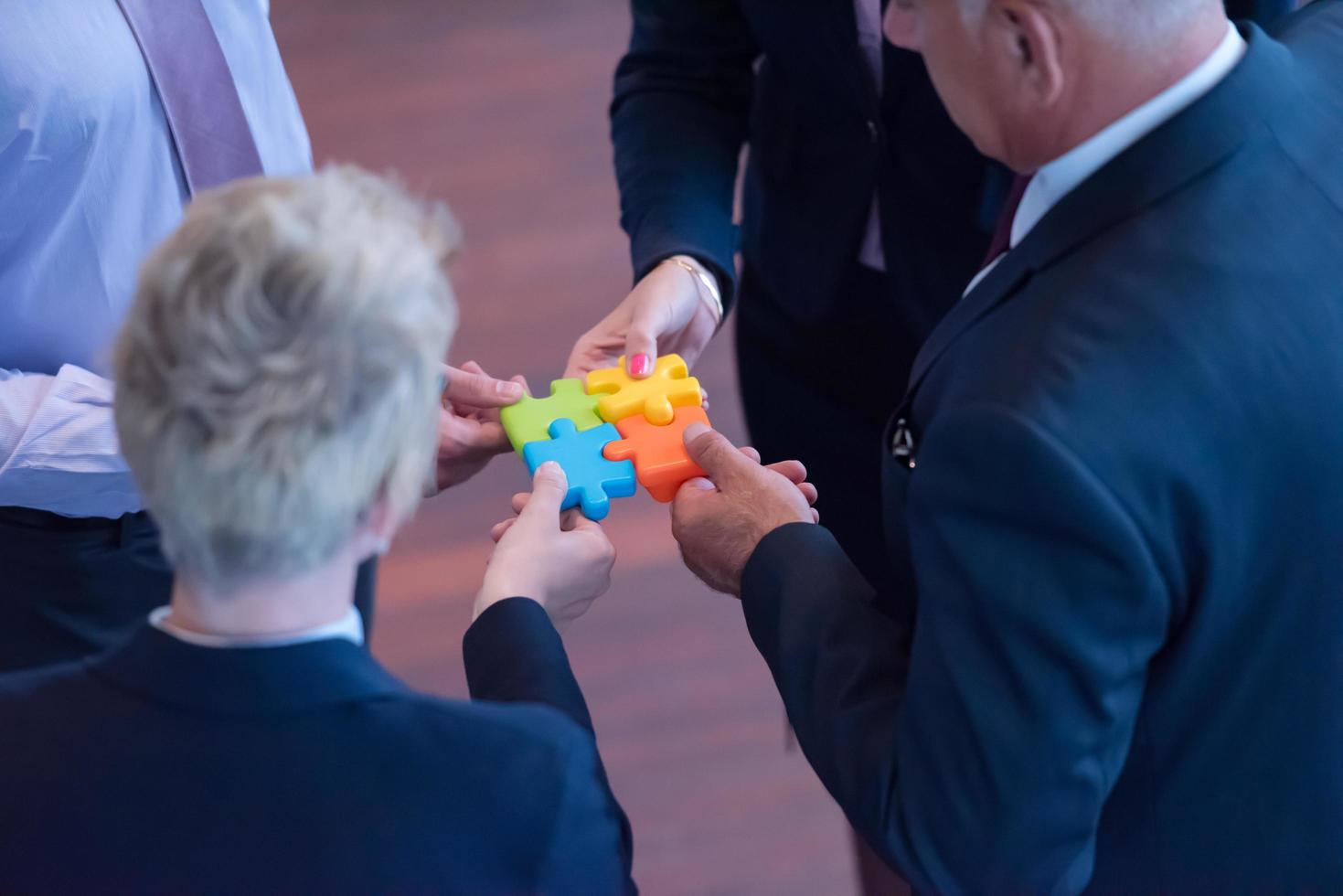 top view of business people group assembling jigsaw puzzle photo