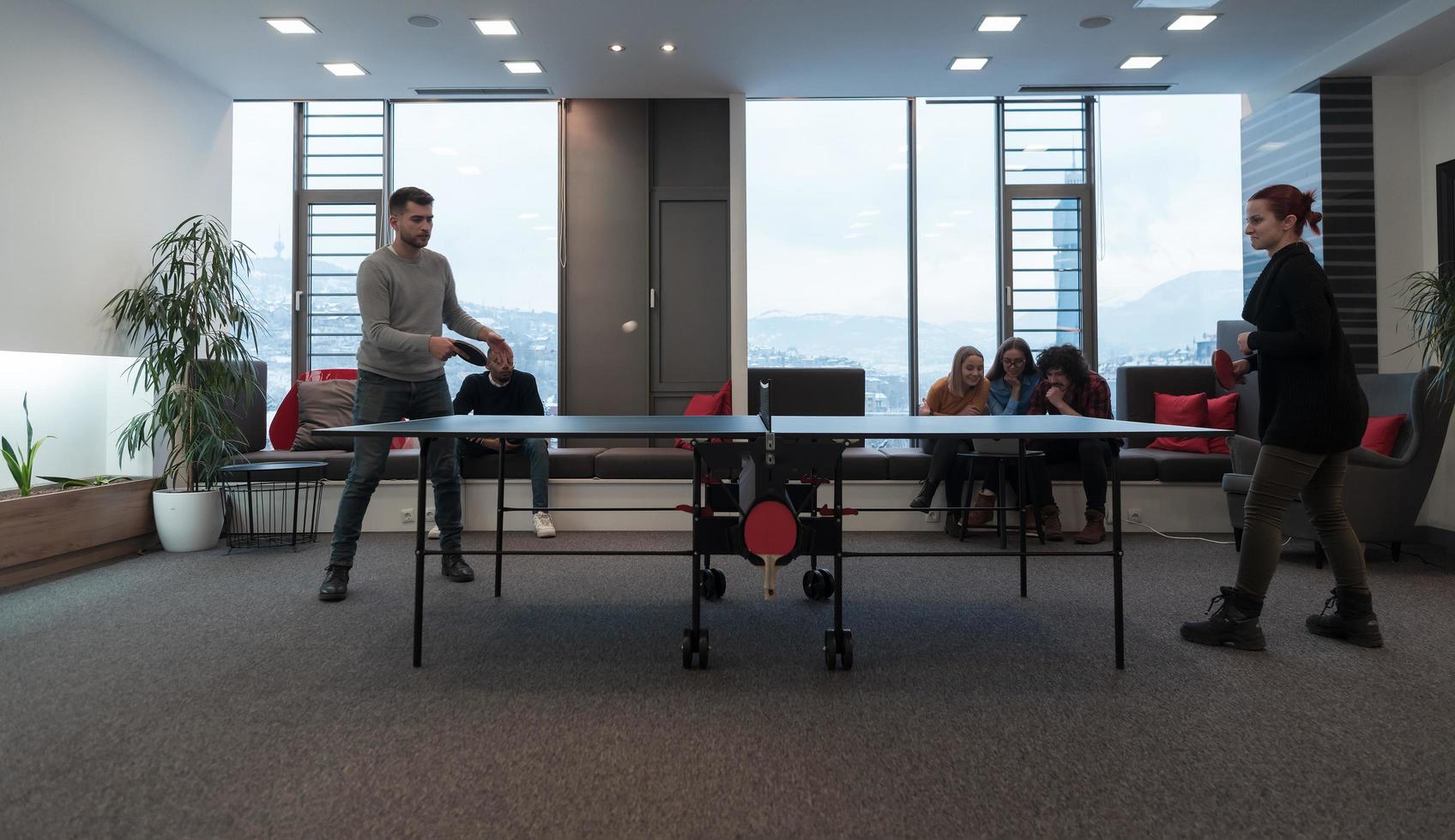 Young start up business man and woman playing table tennis at modern creative office space people group have meeting and brainstorming in background photo