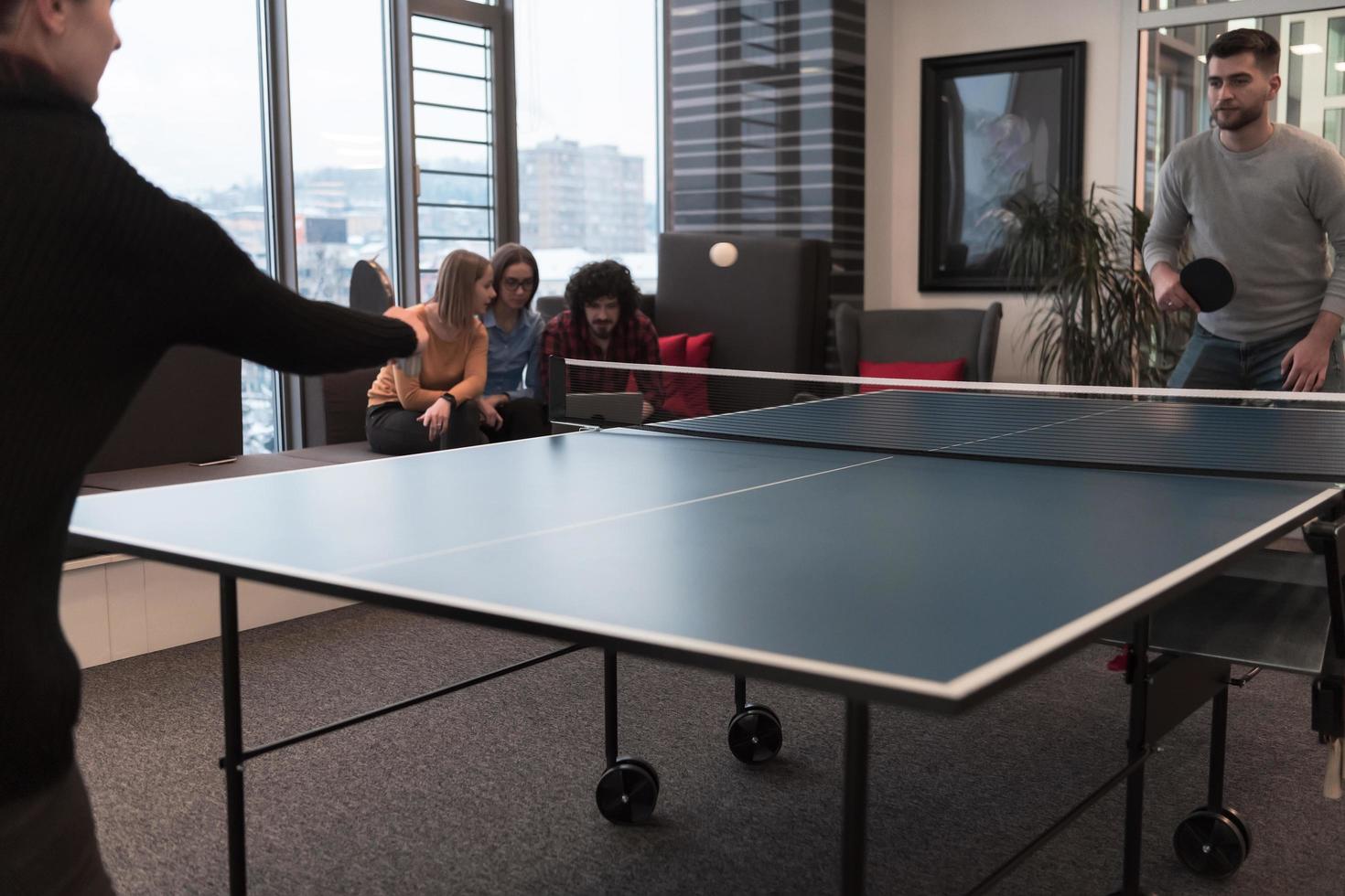 Two young start up business man playing table tennis at modern creative office space people group have meeting and brainstorming in background photo
