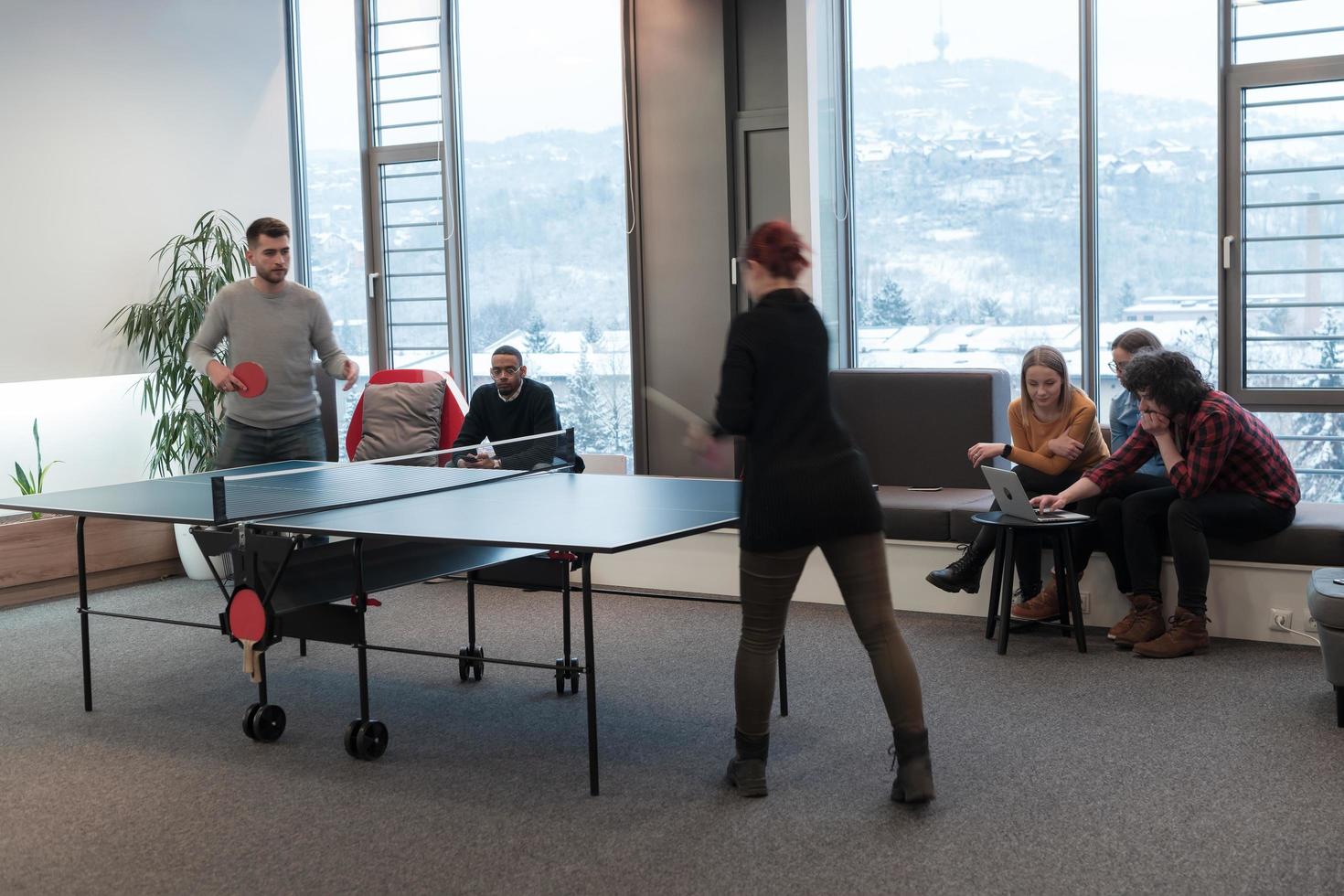 Young start up business man and woman playing table tennis at modern creative office space people group have meeting and brainstorming in background photo