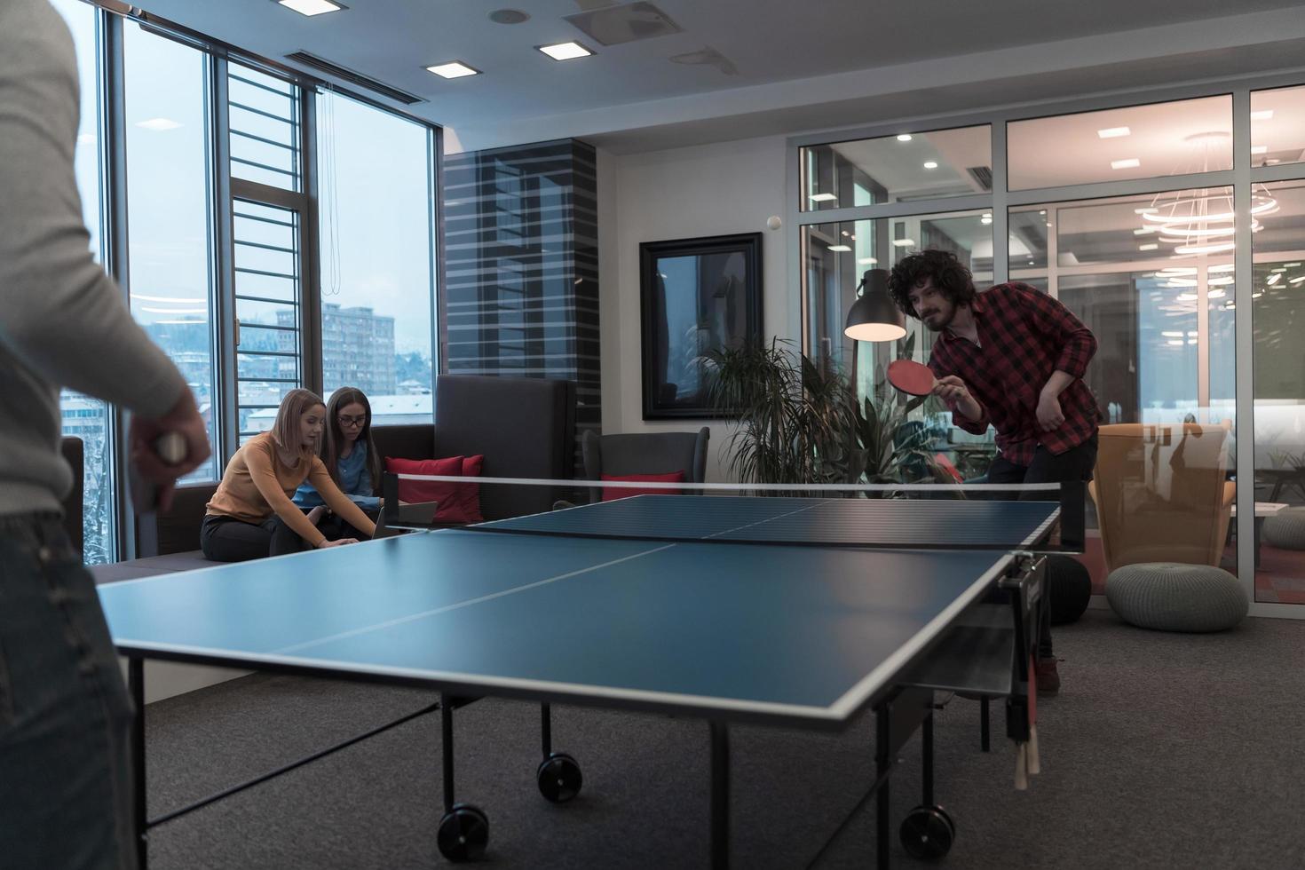 Two young start up business man playing ping pong tennis at modern creative office space people group have meeting and brainstorming in background photo