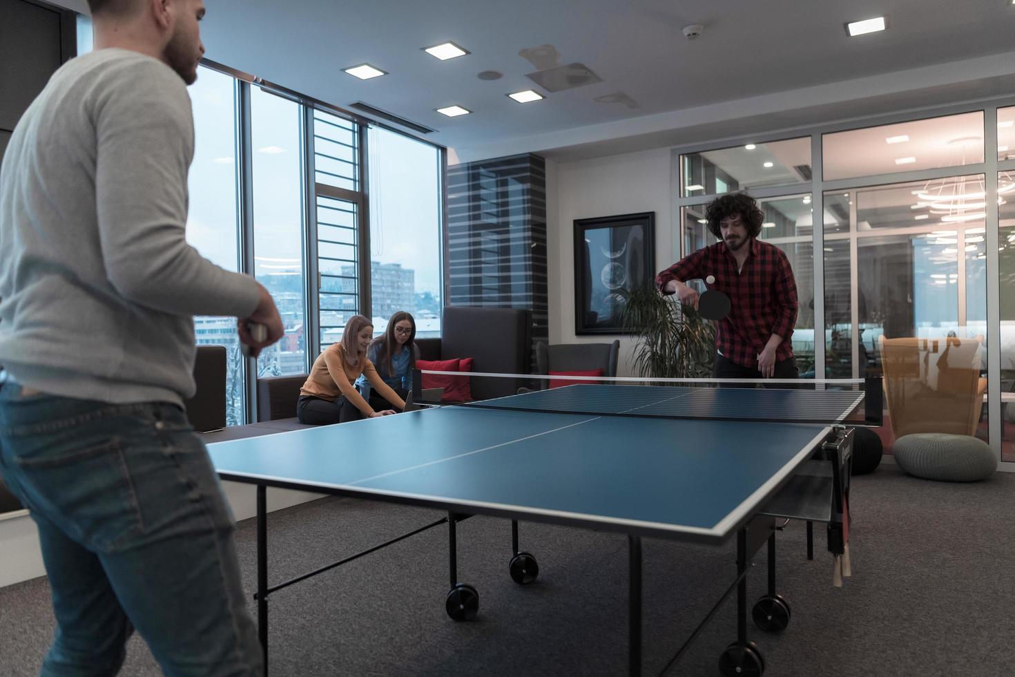 Two young start up business man playing ping pong tennis at modern creative office space people group have meeting and brainstorming in background photo