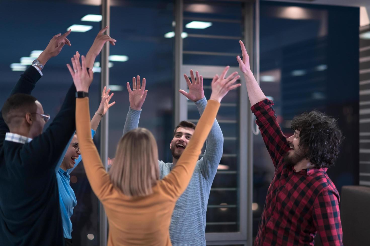 los jóvenes empresarios multiétnicos se divierten celebrando el éxito empresarial compartido o la victoria en el cargo. los empleados diversos multirraciales sonrientes se sienten emocionados de ganar buenos resultados. concepto de trabajo en equipo. foto